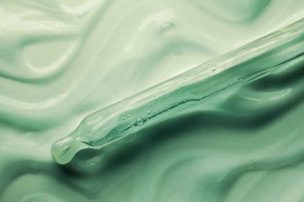 Liquid green gel or serum with pipette textured background