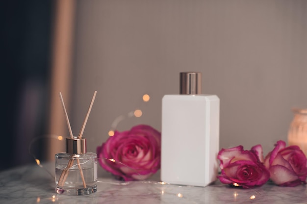 Photo liquid home fragrance in glass bottle with bamboo sticks and rose flowers with white jar of perfume on marble table close up healthy beauty treatment