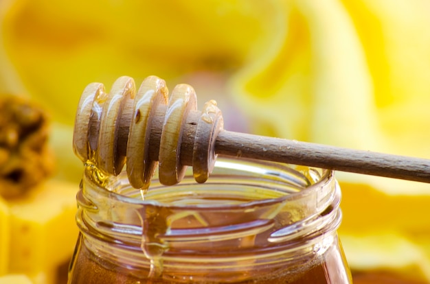 Liquid honey in a glass jar with honey dipper for her