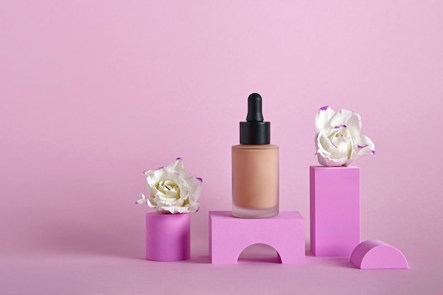 Liquid makeup foundation in bottle and flowers on different geometric podiums Makeup products presentation