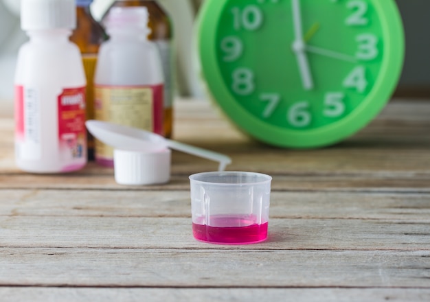 liquid medicine in plastic glass on wooden table.