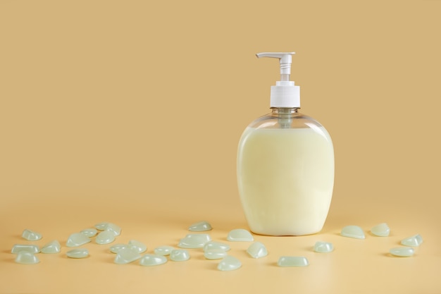 Liquid soap in dispenser on cream surface with light pebbles on table