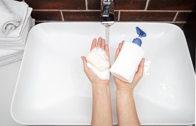 Liquid soap and solid soap in female hands top view. concept of personal hygiene and health.