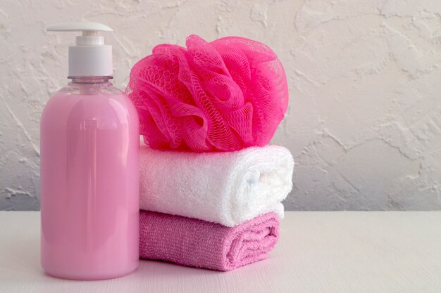 Жидкое мыло и два полотенца на белом фоне.