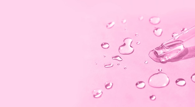 Liquid transparent gel or serum pipette with drops on light pink background