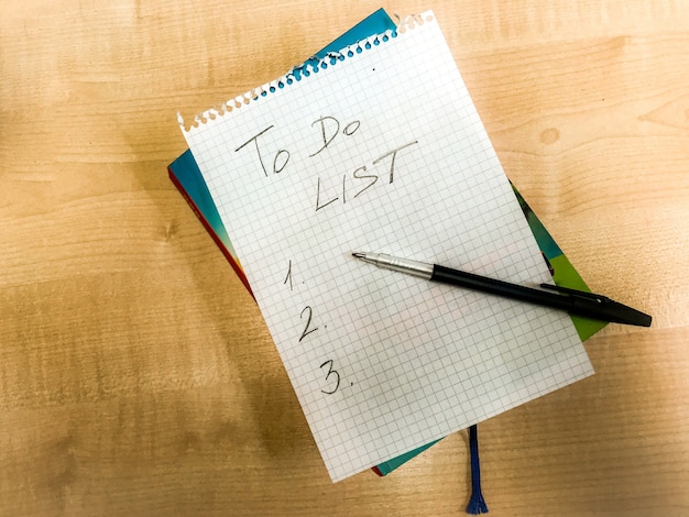 To do list checklist hand written on notepad paper lay on wooden table. fountain pen laying above. High quality photo