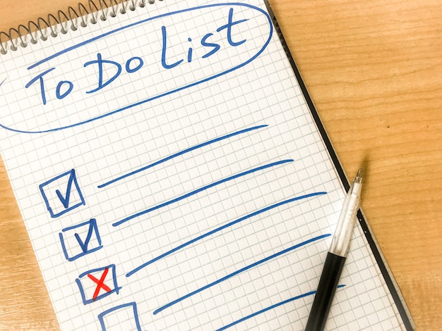 To do list checklist hand written on notepad paper lay on wooden table. penl lay on notepad. High quality photo