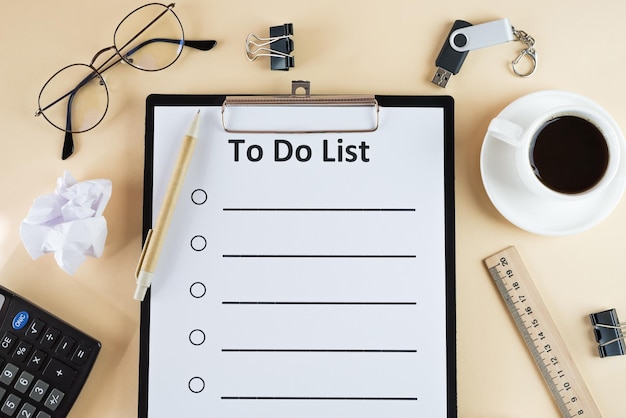 To do list on clipboard with office supplies isolated on beige background