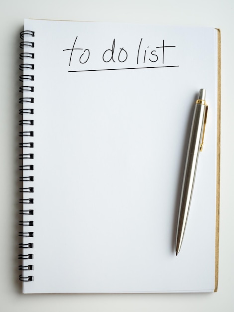 To do list concept to do list handwritten text font with underline on blank space on a white page of simple spiral notebook on white background with silver pen planning and checklist concept