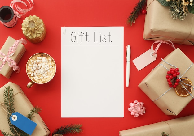 The list of gifts on a white sheet among Christmas gifts