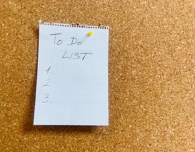 To do list hand written on notepad paper sheet and pinned on cork board. High quality photo