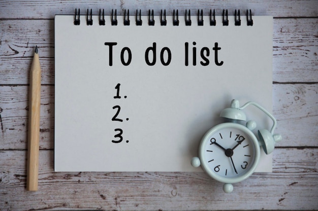 Photo to do list text on notepad - with white alarm clock and pencil conceptual