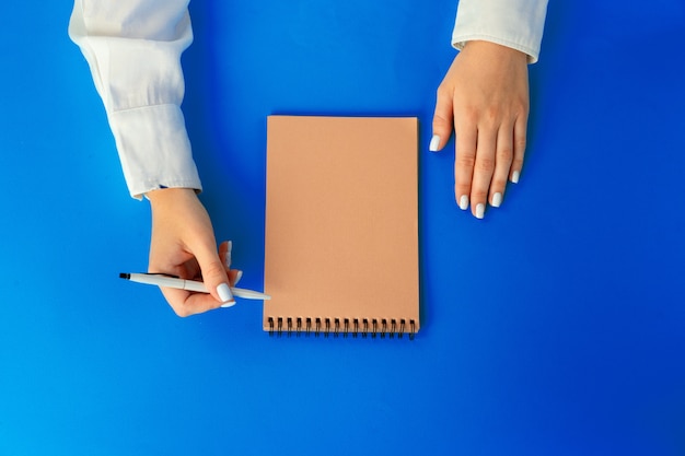 To do list. Top view of female hands writing in notebook