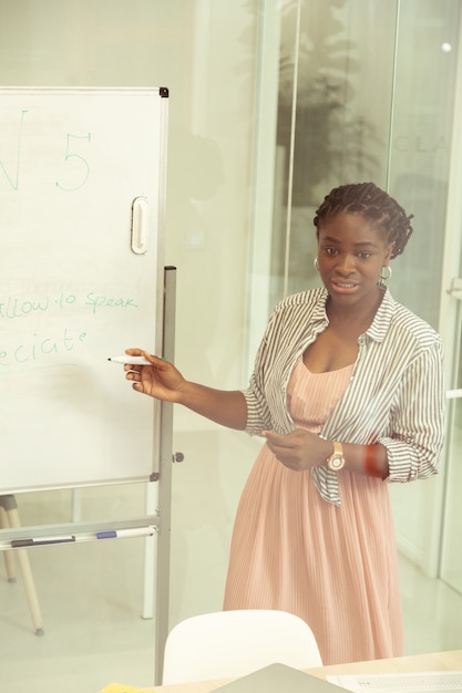 Listen to me. pretty brunette woman writing task on board while
talking to her students