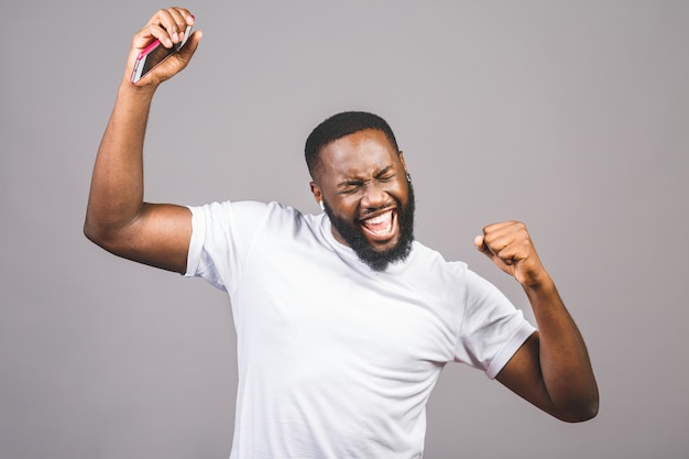 Listening cool music. Young cheerful african american black man moving dancing isolated over grey background.