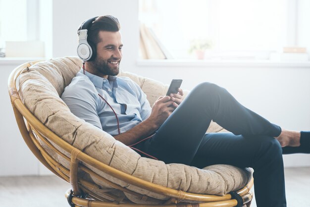 listening to his favorite music. handsome young man in headphones looking at his smart phone