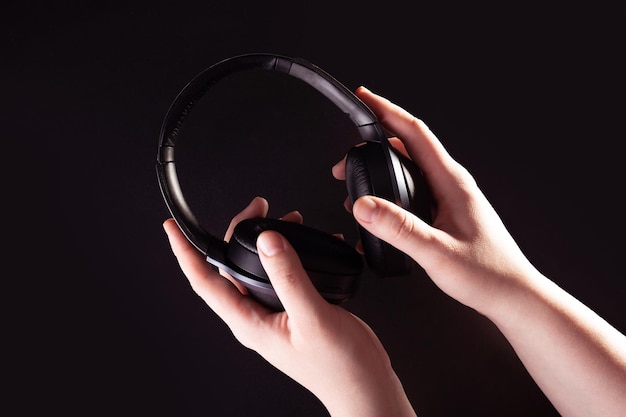 Listening to music social networks leads to relaxation\
headphone wireless in hand black background