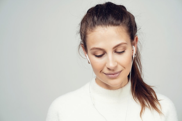 Listening to music with headphones looking at the camera a brunette woman