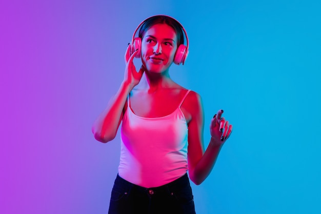 Listening to music with headphones Young caucasian womans portrait on gradient