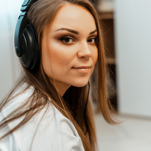 Listening to music. Young beautiful girl with big headphones on her head. Close-up. Leisure and music.