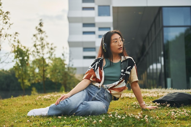 Listens to the music in headphones Young asian woman is outdoors at daytime