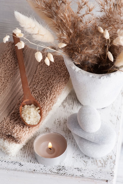 Lit aroma candle and golden dry flowers on rustic background