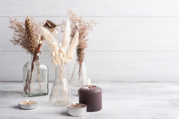 Lit aroma candles and dry flowers on rustic background. Spa arrangement in monochrome style