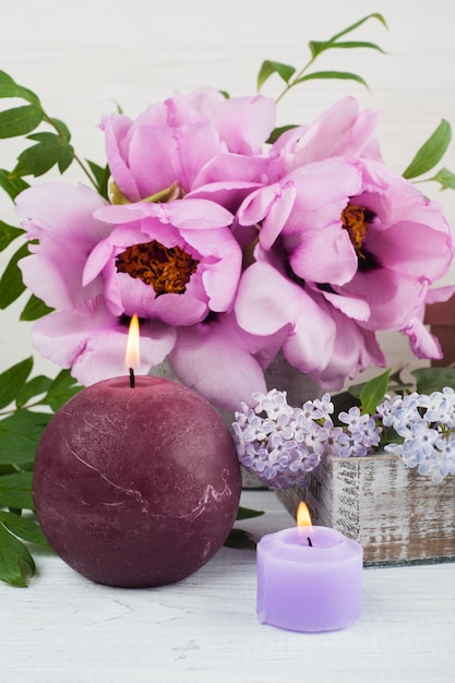 Lit candles, peonies and lilac flowers