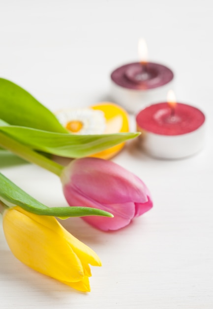 Lit candles and yellow pink tulips