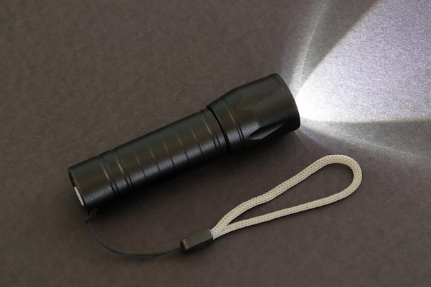 A lit flashlight with its lanyard