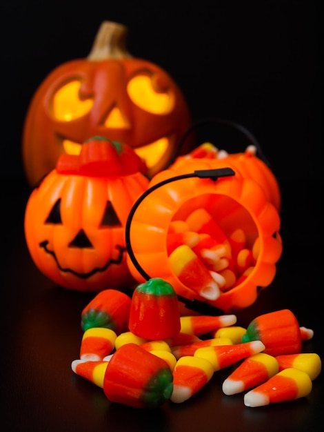 Lit jack-o'-lantern with Halloween pumpkin bags on black background.