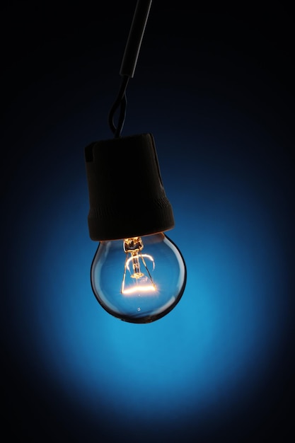 A lit light bulb on blue background