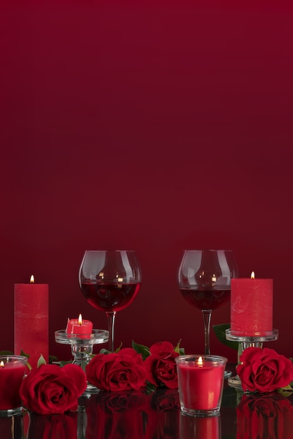 Lit red candles in transparent candlesticks illuminate glasses with wine surrounded