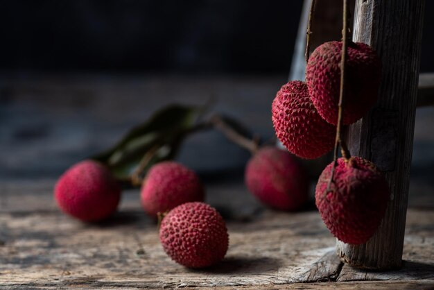 Photo litchi is placed in a wooden plate peeled or unopened on a dark wood grain table