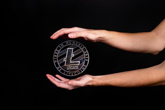 Litecoin coin and a man's hand on a black background