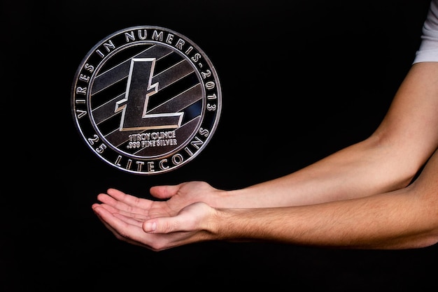 Litecoin munt en de hand van een man op een zwarte achtergrond