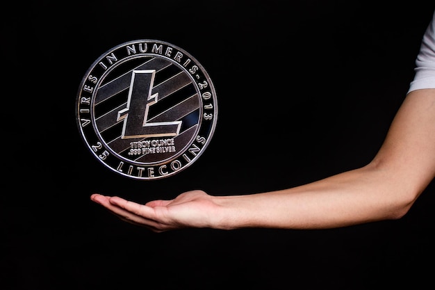 Litecoin munt en de hand van een man op een zwarte achtergrond