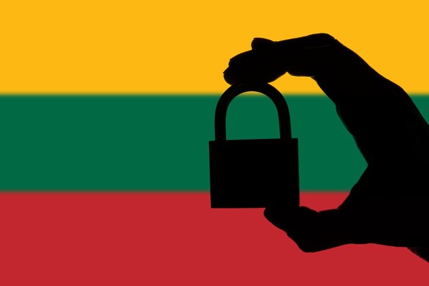 Lithuania security Silhouette of hand holding a padlock over national flag