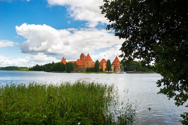 Lithuania. View on Trakai castle across lake and white yacht under sail