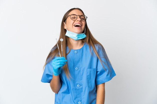 Lithuanian woman dentist holding tools over isolated wall laughing