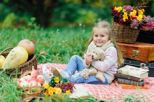 Litlle girl sitting on a blanket on the grass