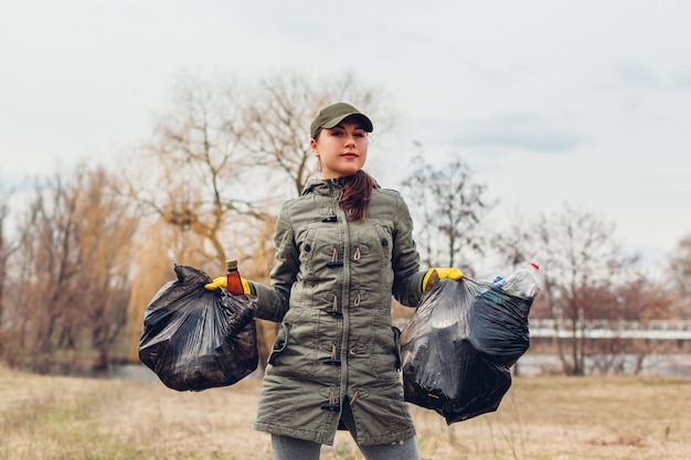 Litter picking. Woman volunteer cleaning up the trash in park. Picking up garbage outdoors. Ecology and environment