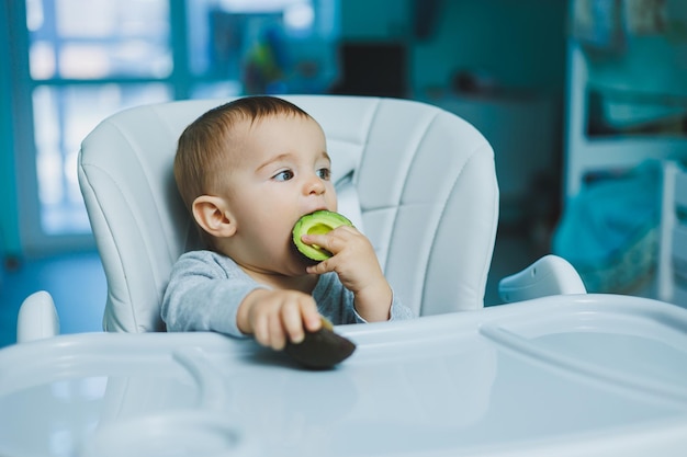 Little adorable baby eating avocado Vitamin and healthy food for small children Portrait of beautiful child of 8 months