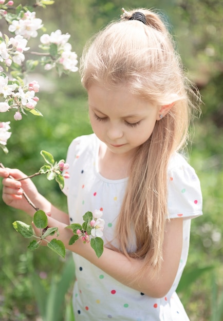 リンゴ園の開花の木の中で小さな愛らしい女の子