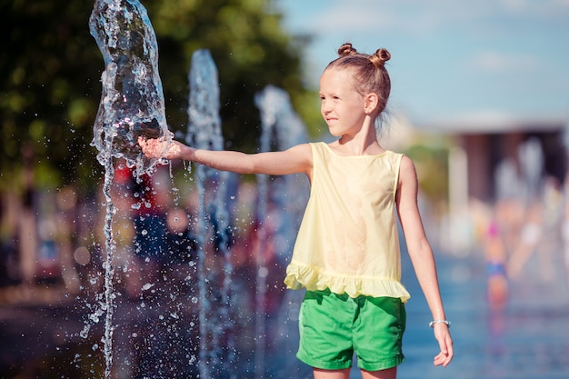 Photo little adorable girl have fun in street fountain at hot sunny day