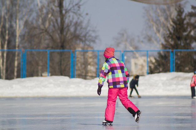 アイスリンクの小さな愛らしい女の子-スケートスポーツ、望遠