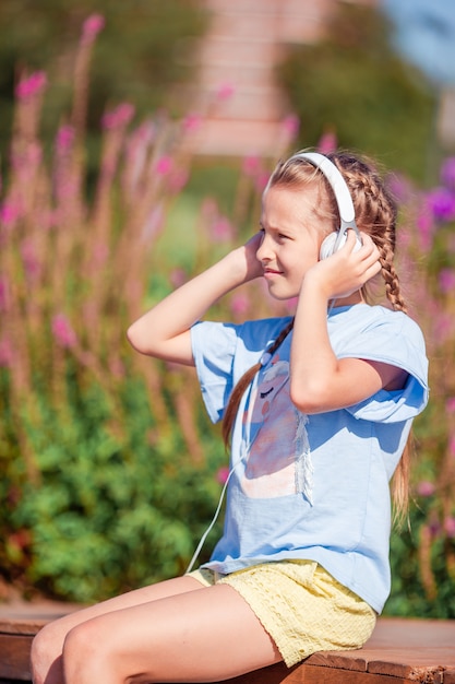 Little adorable girl listening music in the park