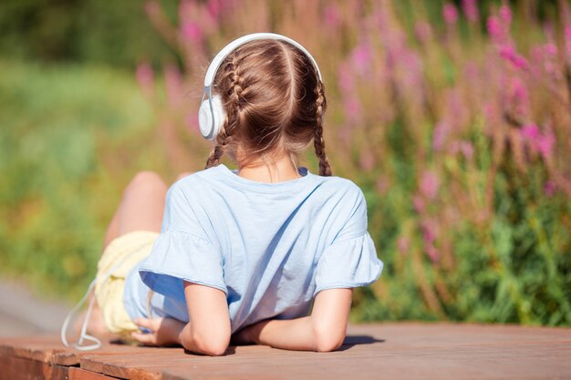 Little adorable girl listening music in the park