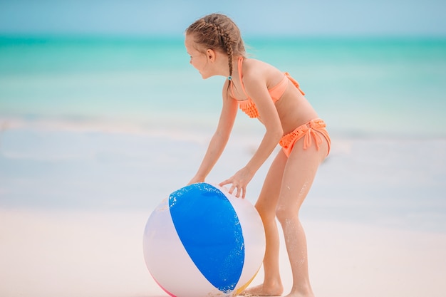 Маленькая прелестная девушка играя на пляже с шариком