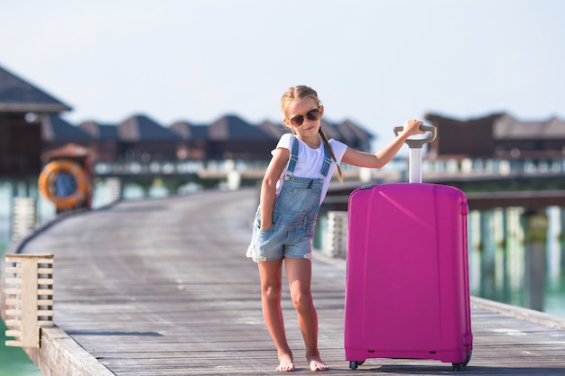 Piccola ragazza adorabile con grandi bagagli durante le vacanze estive